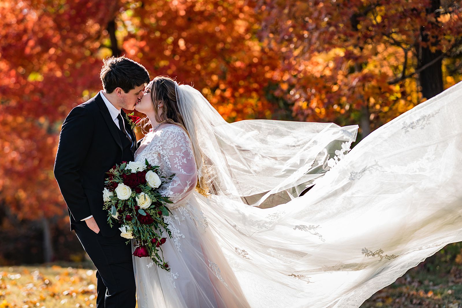 windswept bride and groom kissing at their fall wedding