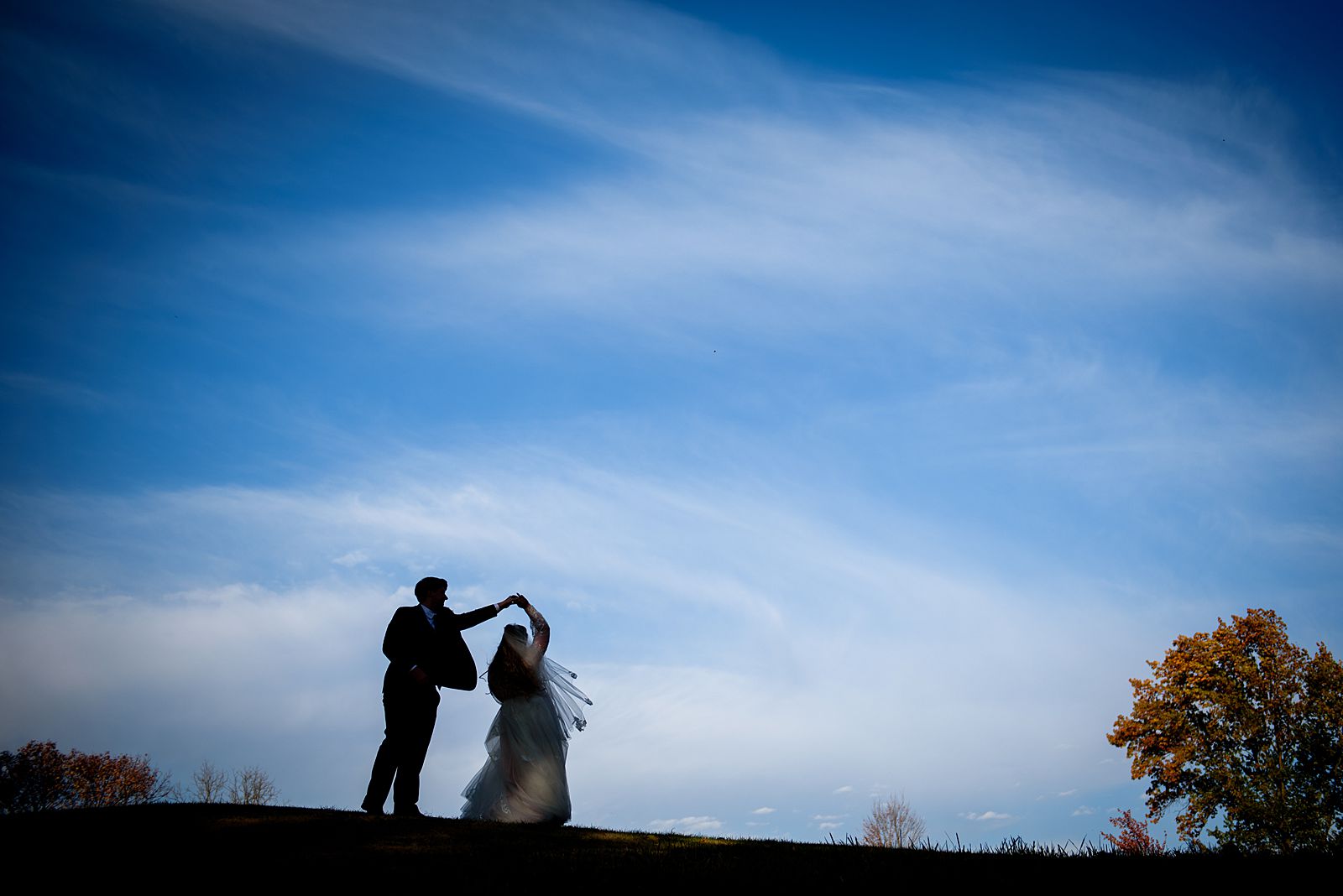 groom twirling his bride on a hill